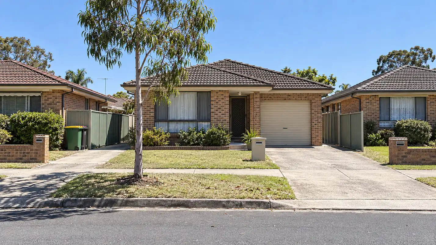 A quiet street of brick-veneer houses in Western Sydney at midday.